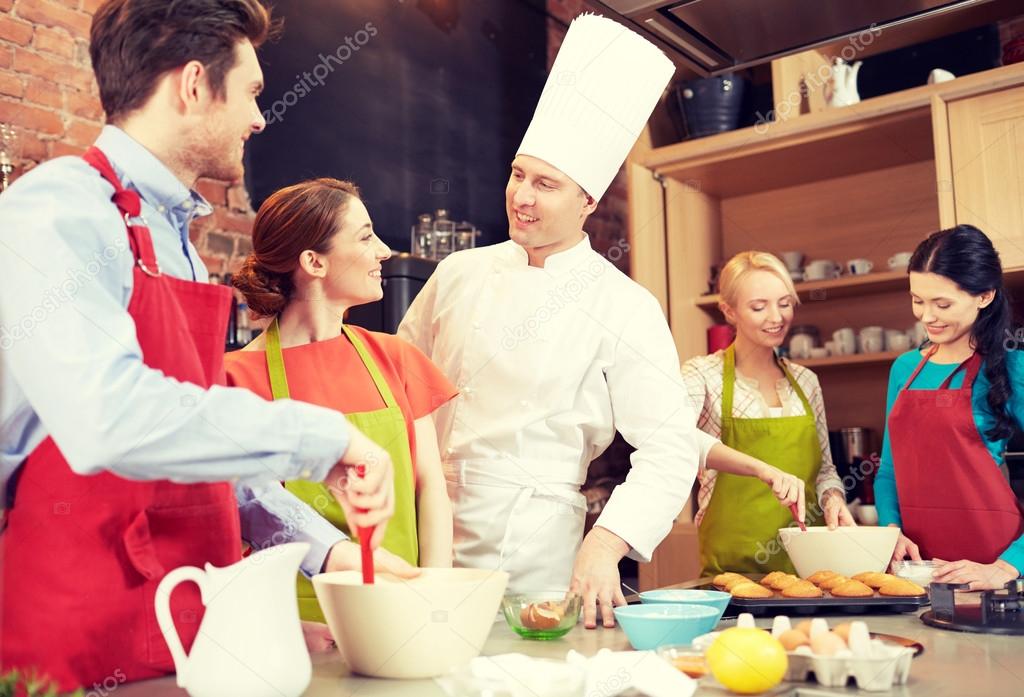 Happy friends and chef cook baking in kitchen — Stock Photo