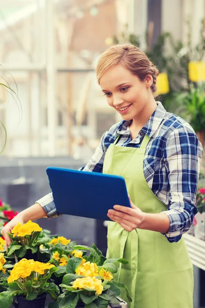 Happy woman with tablet pc in greenhouse — Stock Photo, Image