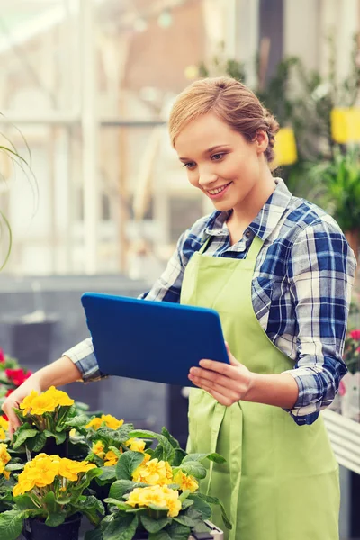 Gelukkige vrouw met tablet pc in kas — Stockfoto