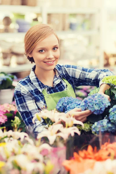 Lycklig kvinna ta hand om blommor i växthus — Stockfoto