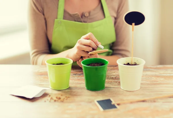 Close up of woman writing name on garden sign — Stock Photo, Image