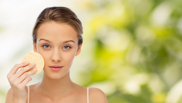 Mujer joven limpiando la cara con esponja exfoliante — Foto de Stock