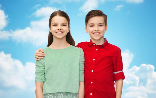 Happy boy and girl hugging over blue sky — Stockfoto