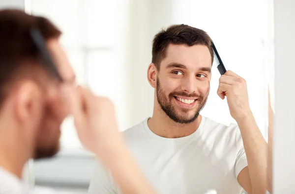 Uomo felice spazzolando i capelli con pettine in bagno — Foto Stock