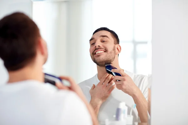 Чоловік голить бороду з тримером у ванній — стокове фото