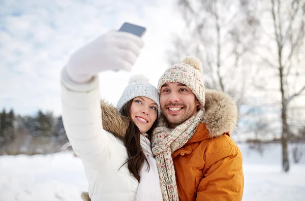 Feliz pareja tomando selfie por teléfono inteligente en invierno — Foto de Stock