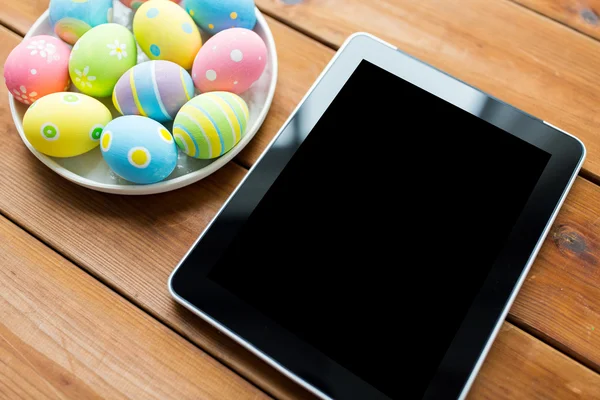 Close up of easter eggs and blank tablet pc — Stock Photo, Image