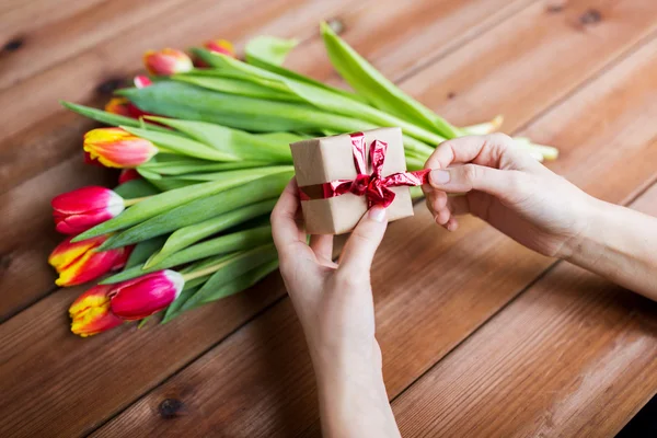 Close up de mulher com caixa de presente e flores de tulipa — Fotografia de Stock