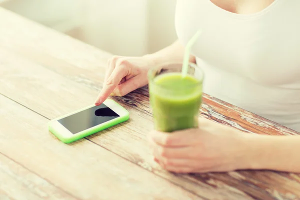 Close up of woman with smartphone and green juice — Stock Photo, Image