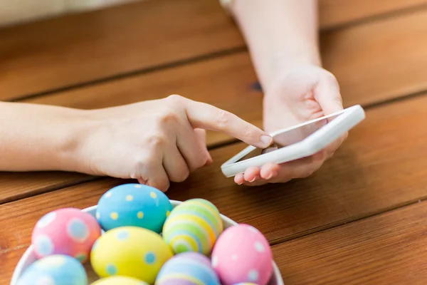 Close up of hands with easter eggs and smartphone — Stock Photo, Image