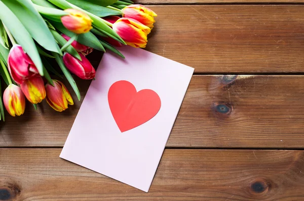 Close up of flowers and greeting card with heart — Stock Photo, Image