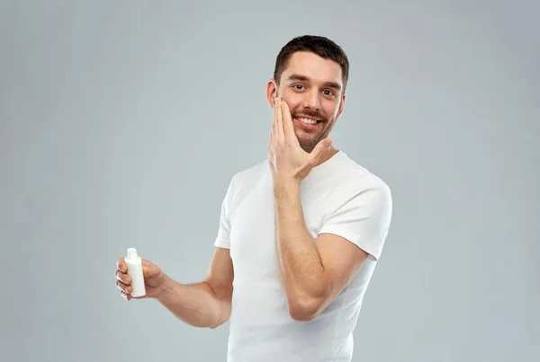 Glad ung man tillämpa kräm eller lotion att möta — Stockfoto