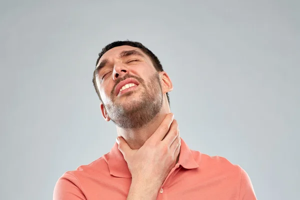 Человек трогает шею и страдает от боли в горле — стоковое фото