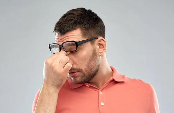 Tired man with eyeglasses touching nose bridge — Stock Photo, Image