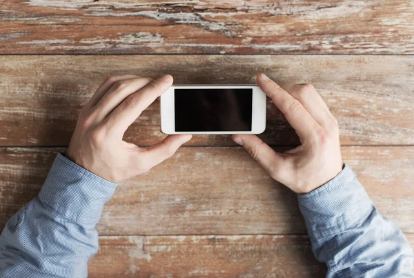 Close up van mannelijke handen met smartphone op tafel — Stockfoto