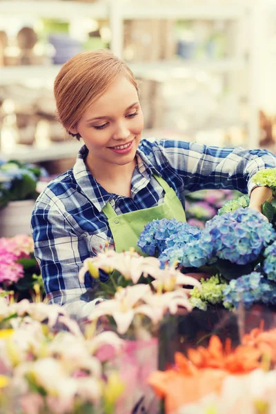 Lycklig kvinna ta hand om blommor i växthus — Stockfoto