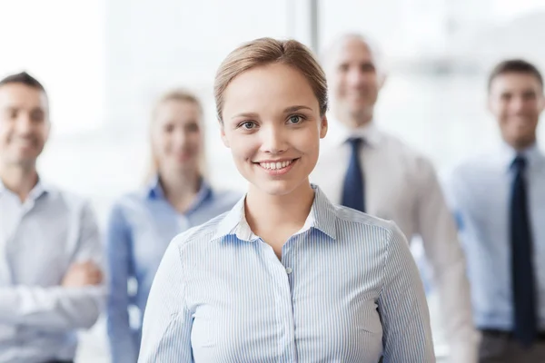 Smiling businesswoman with colleagues in office — Stock Photo, Image