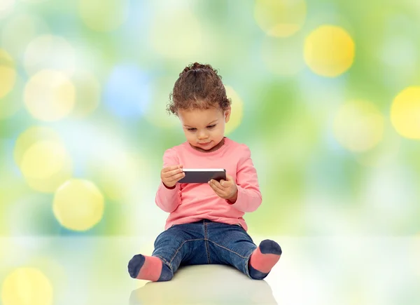 Улыбающаяся маленькая девочка, играющая со смартфоном — стоковое фото