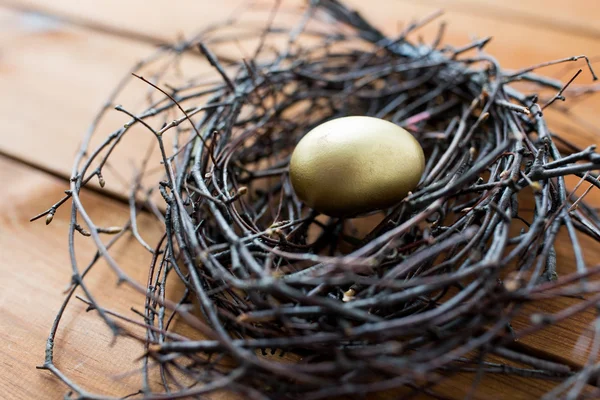 Närbild av gyllene påsk ägg i boet på trä — Stockfoto
