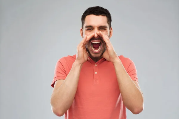 Irritado gritando homem em t-shirt sobre fundo cinza — Fotografia de Stock