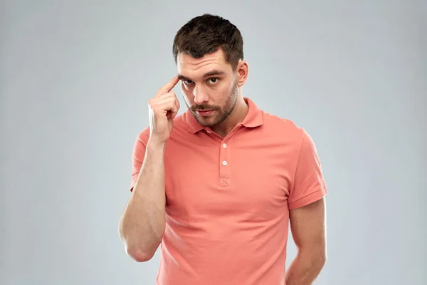 Man with finger at temple over gray background — Stock Photo, Image