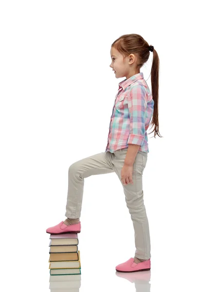 Feliz niña pisando la pila del libro — Foto de Stock