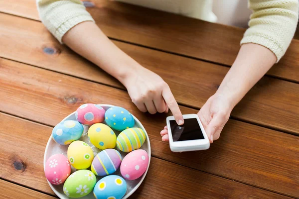 Close up of hands with easter eggs and smartphone — Stock Photo, Image