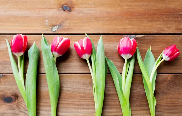 Gros plan de fleurs de tulipes rouges sur une table en bois — Photo