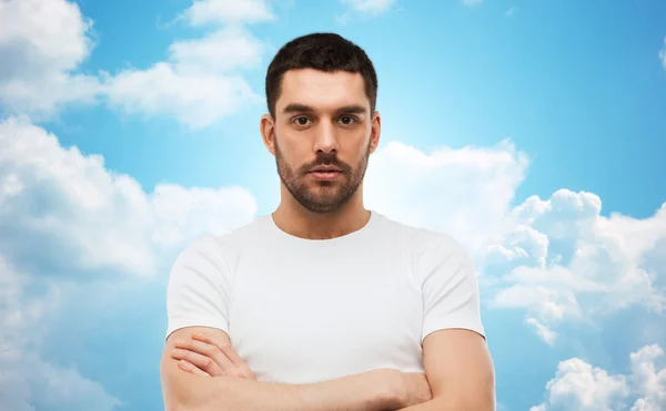 Young man with crossed arms over blue sky — Stockfoto