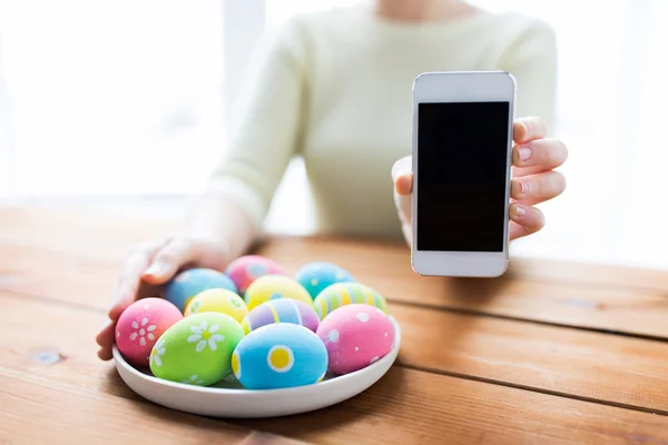 Close up of hands with easter eggs and smartphone — Stock Photo, Image