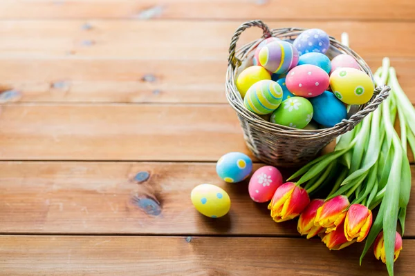 Close up of easter eggs in basket and flowers — Stock Photo, Image