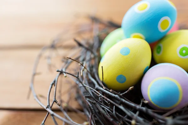 Primer plano de huevos de Pascua de colores en el nido en la madera —  Fotos de Stock