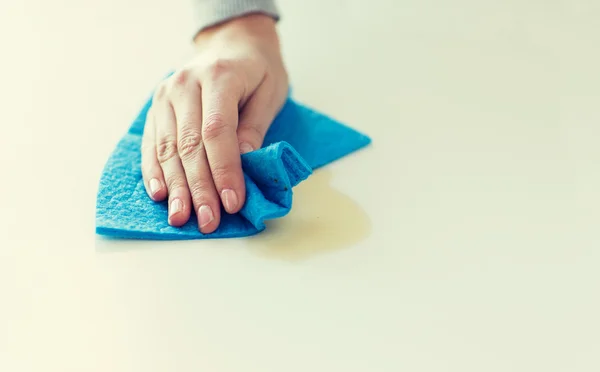 close up of hand cleaning table surface with cloth