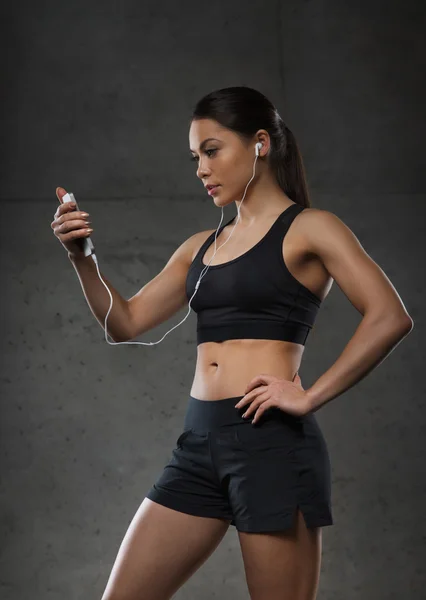 Femme avec smartphone et écouteurs dans la salle de gym — Photo