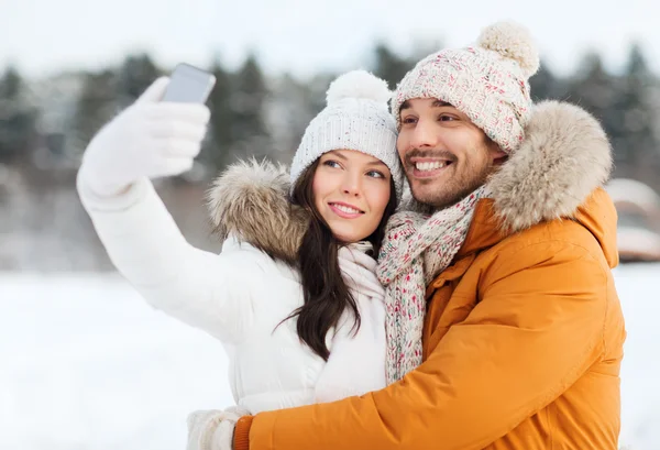 Casal feliz tomando selfie por smartphone no inverno — Fotografia de Stock