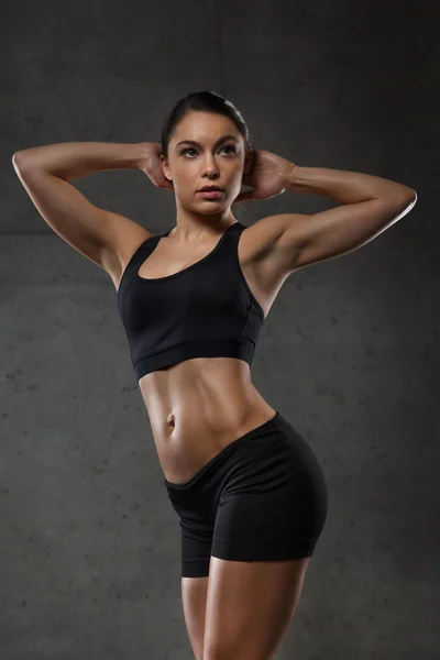 Mujer joven posando y mostrando músculos en el gimnasio — Foto de Stock