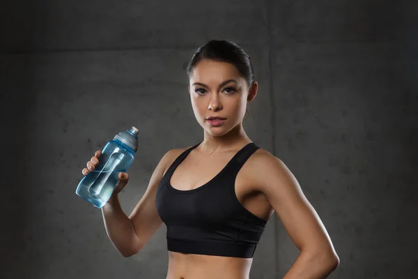 Woman drinking water from bottle in gym — Stock Photo, Image