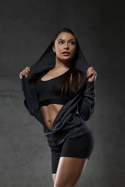 Mujer joven posando y mostrando músculos en el gimnasio — Foto de Stock