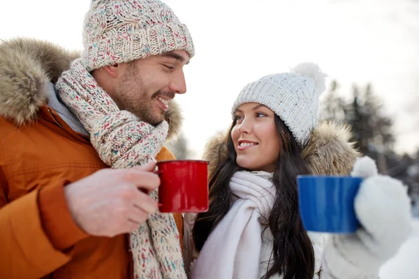 Happy couple with tea cups over winter landscape — Stock Photo, Image