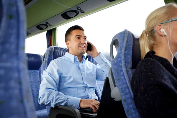 Щасливий чоловік зі смартфоном і ноутбуком у туристичному автобусі — стокове фото