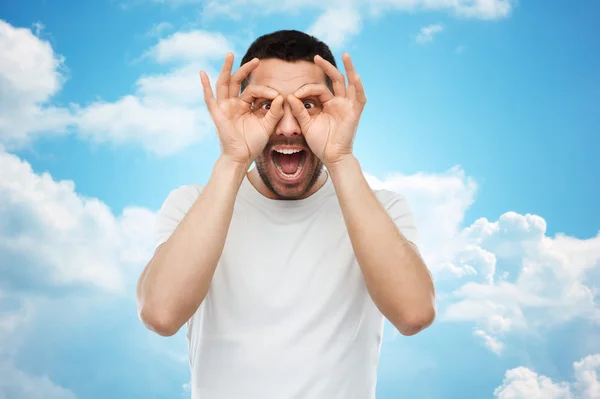 Man making finger glasses over blue sky — Φωτογραφία Αρχείου