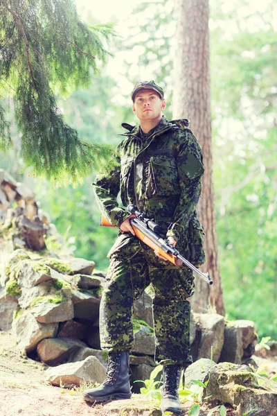 Jovem soldado ou caçador com arma na floresta — Fotografia de Stock