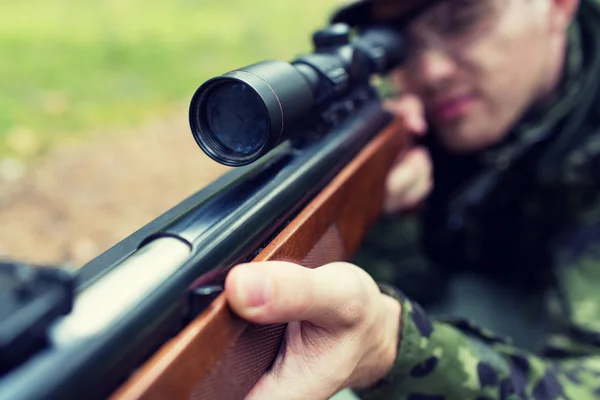 Close up of soldier or hunter with gun in forest — Stock Photo, Image