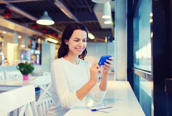 Mujer sonriente con teléfono inteligente en la cafetería — Foto de Stock