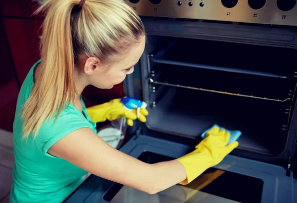 Happy woman cleaning cooker at home kitchen — Stock Photo, Image