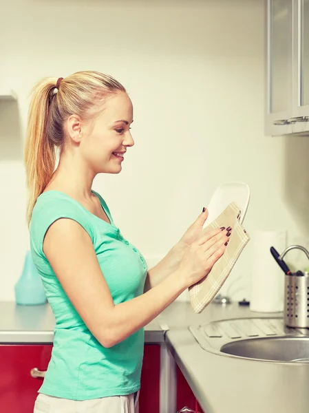 Mulher feliz limpando pratos em casa cozinha — Fotografia de Stock