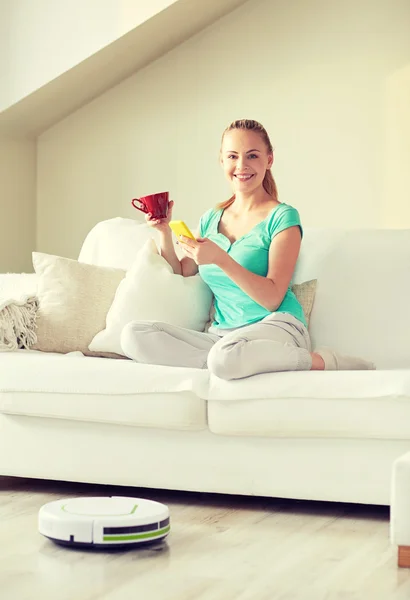 Happy woman with smartphone drinking tea at home — Stock Photo, Image