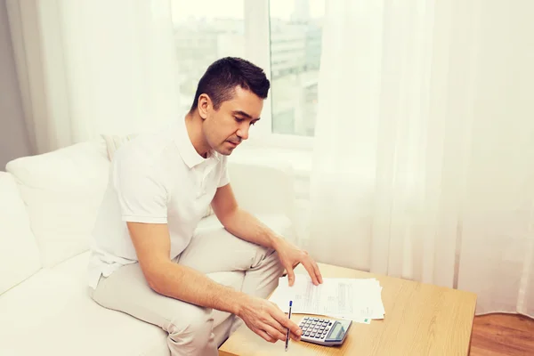 Man met papieren en rekenmachine thuis — Stockfoto