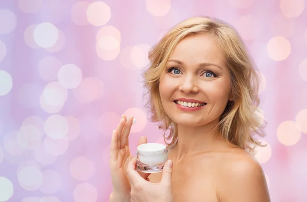 Mulher feliz aplicando creme em seu rosto — Fotografia de Stock