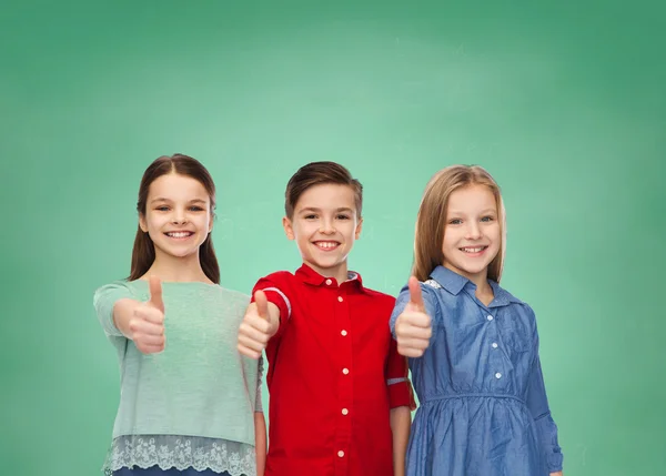 Happy children showing thumbs up over green board — Stockfoto